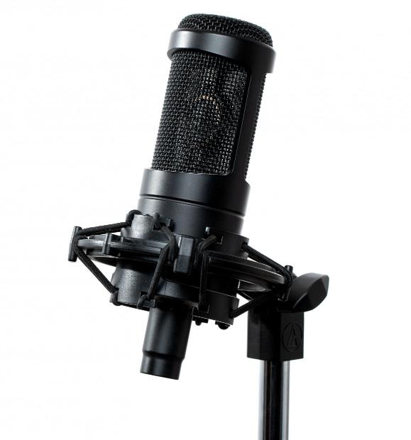 Close-up of a vintage microphone and notebook on a sound-treated desk.